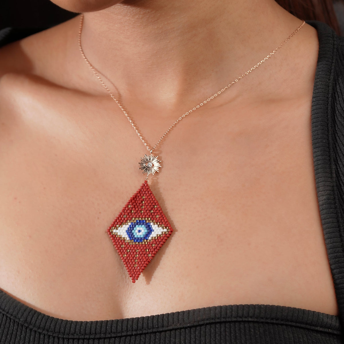 Model wearing a red and blue evil-eye beaded pendant on a rose-gold-tone chain
