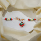Rose-gold bracelet with crystal crossbar, red and green beaded diamond charm and striped bead tubes