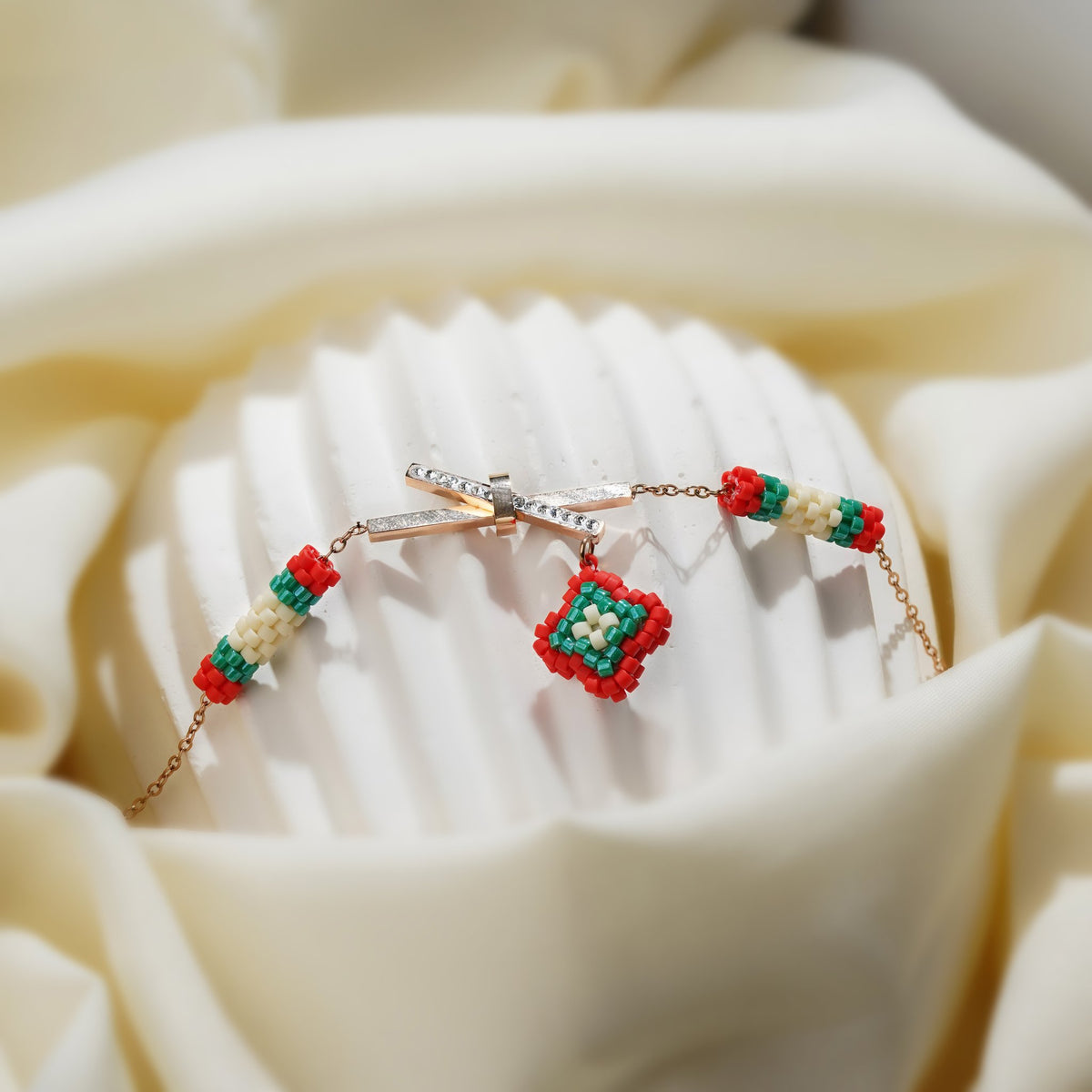 Close-up of the crystal crossbar and red, green and cream beaded diamond charm on a fluted stand