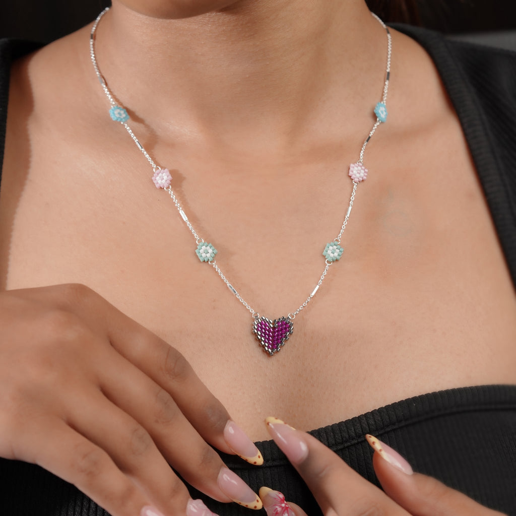 Model wearing silver daisy station necklace with purple beaded heart pendant
