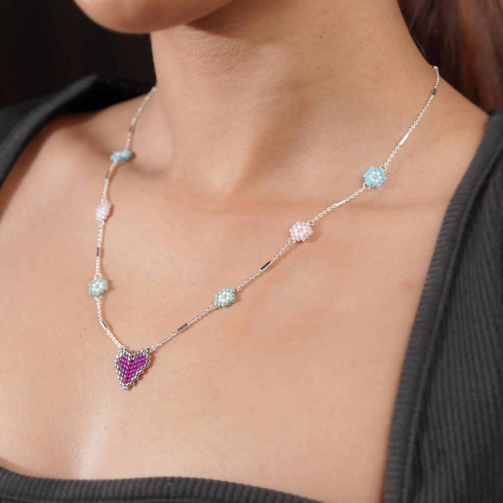 Side view of model wearing pastel daisy station necklace with purple heart