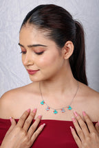Duckling charm necklace worn with a red top, model's hand resting at the neckline