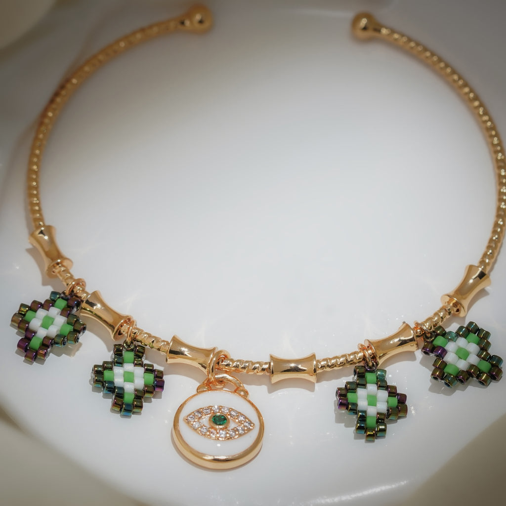 Close-up of green, white and iridescent beaded charms around a white enamel evil-eye disc