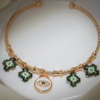 Close-up of green, white and iridescent beaded charms around a white enamel evil-eye disc