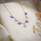 Angled view of cobalt evil-eye charms, rose-gold butterflies and crystal butterfly on a faceted chain