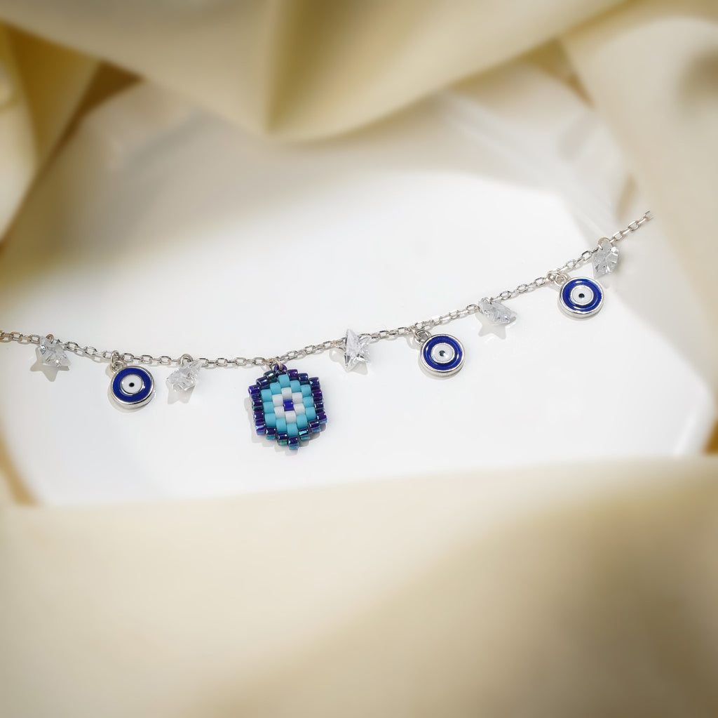 Silver charm bracelet with beaded evil eye, blue evil-eye discs and crystal star charms