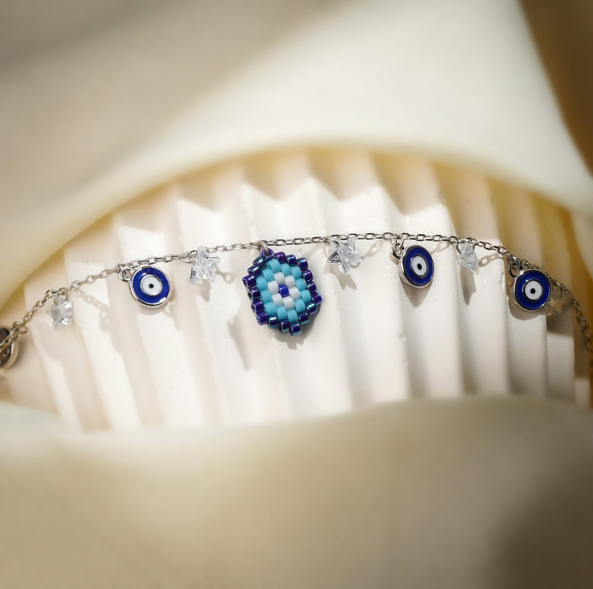 Close-up of turquoise and cobalt beaded evil eye charm between blue eye discs on silver chain