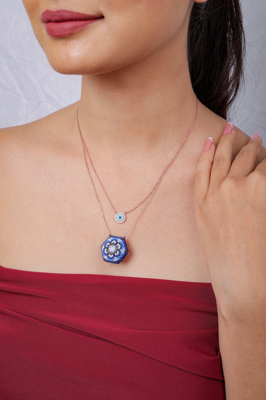 Layered rose-gold-tone necklace with evil-eye disc and cobalt hexagon beaded mandala pendant