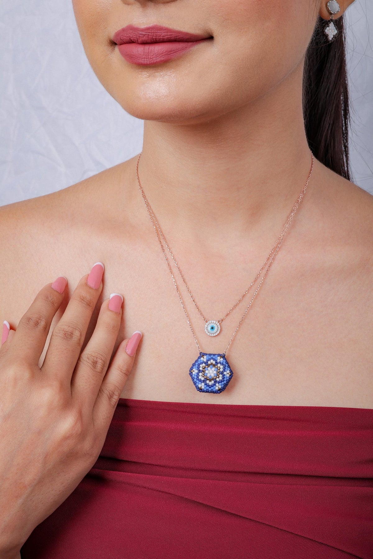 Layered evil-eye and cobalt mandala necklace on a model, hand resting at the chest