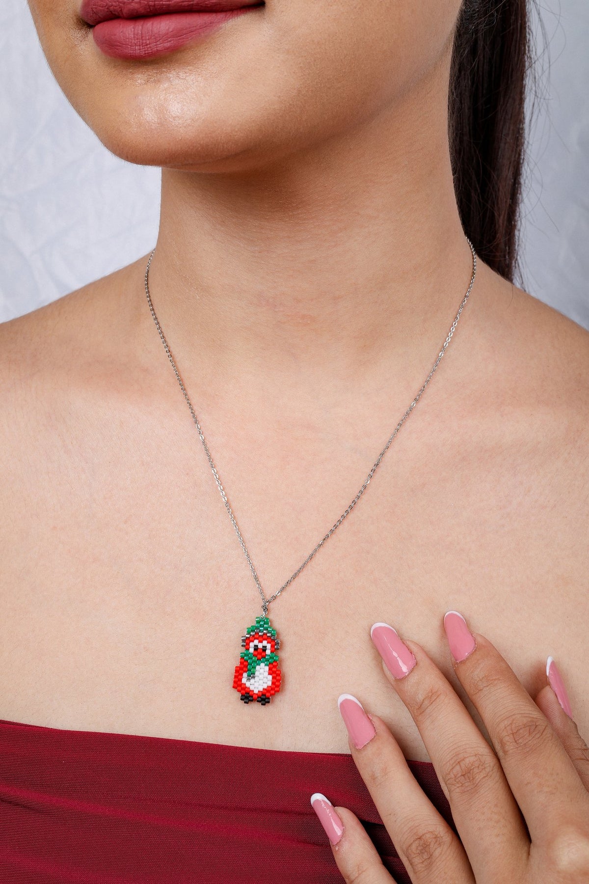 Close view of festive beaded penguin pendant on silver chain worn by model