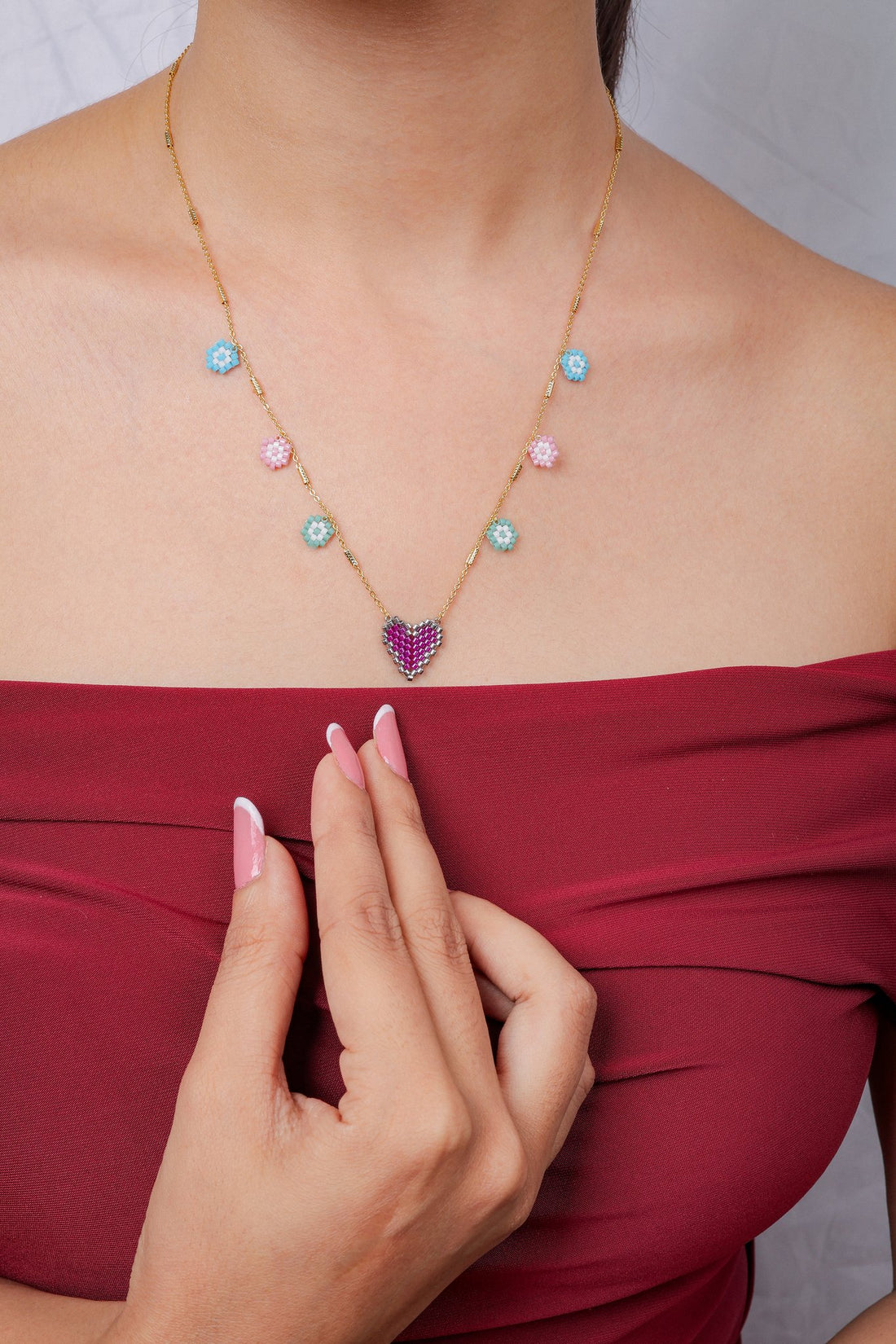 Gold chain necklace with a fuchsia beaded heart pendant and six pastel beaded flower charms