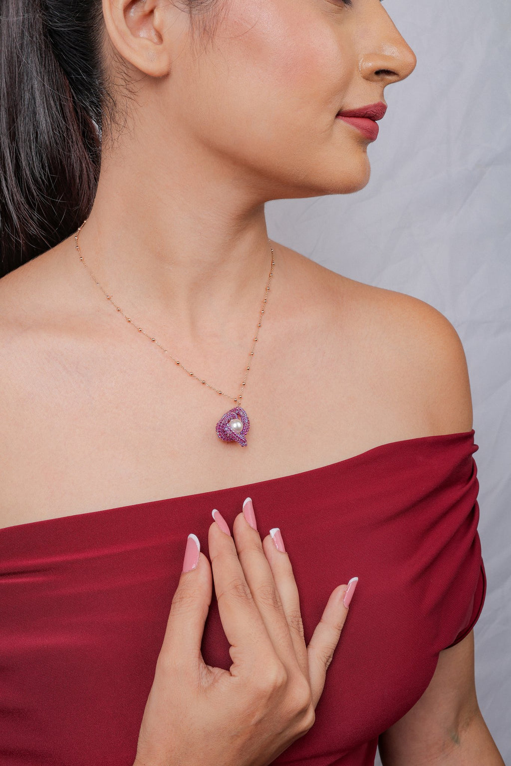 Side profile of a model wearing a rose-gold-tone chain with a fuchsia beaded knot pendant