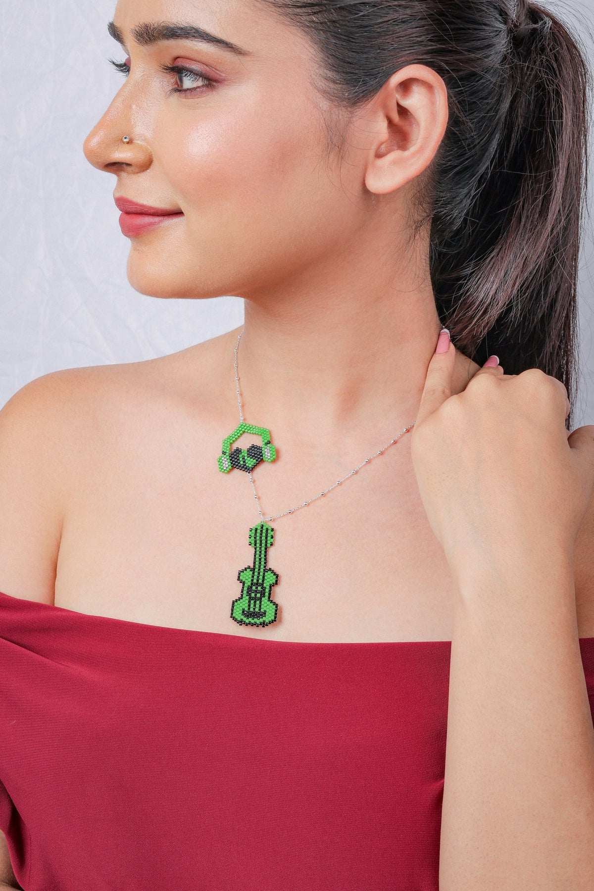 Side view of the green guitar charm necklace on a silver chain