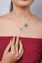 Model wearing silver chain necklace with silver hamsa hand charm and green beaded hamsa charm