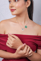 Model looking aside, wearing silver chain with silver hand and green beaded hamsa charms