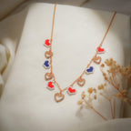 Rose-gold chain necklace with red and navy pixel-heart charms and crystal open hearts on cream silk
