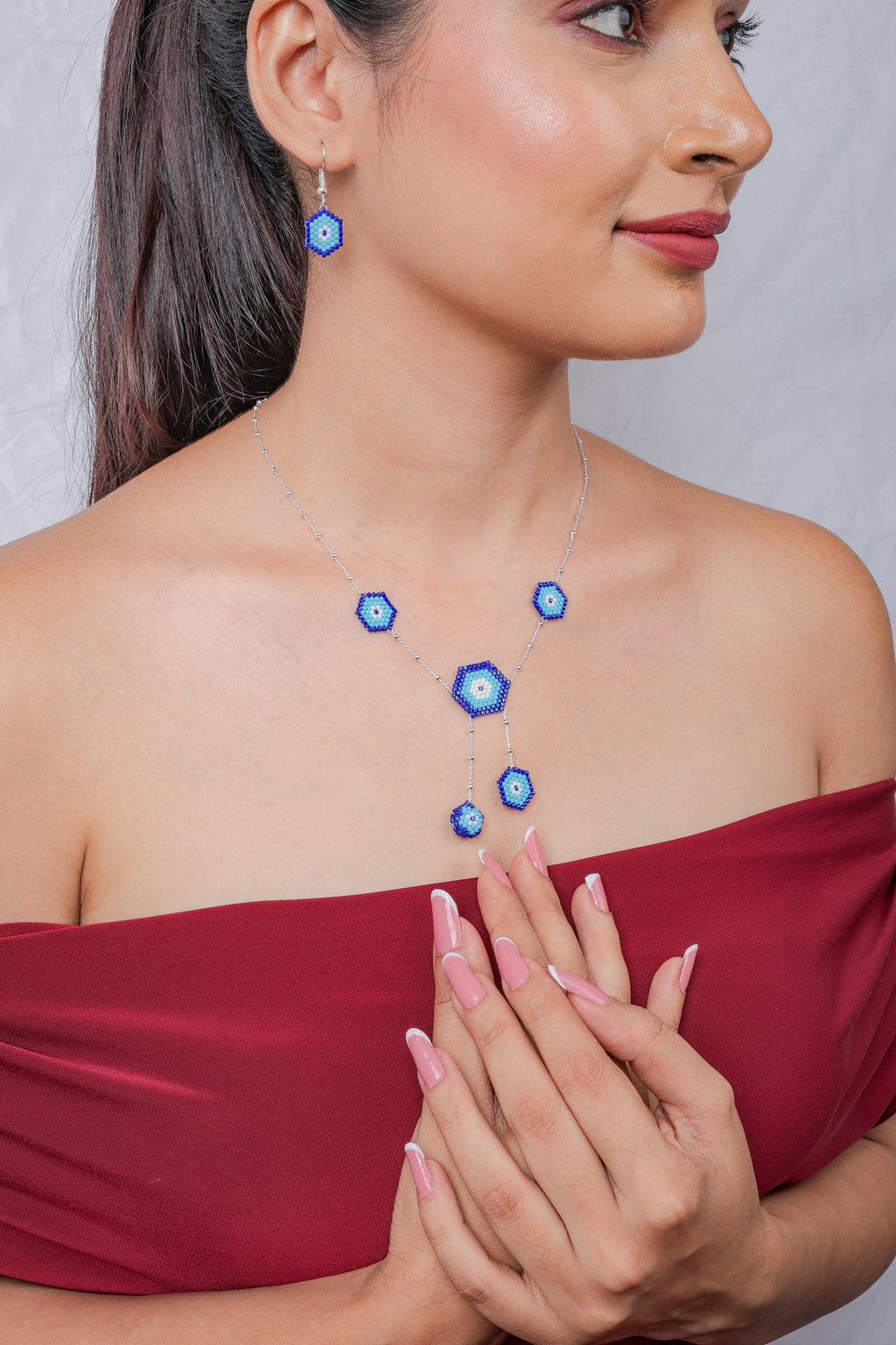 Model wearing blue hexagon evil eye necklace with Y-drop and matching earrings