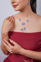 Model in red dress wearing silver chain with beaded evil eye hexagons and hexagon earring