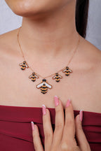 Rose-gold bee charm necklace on model, with a large centre bee and four smaller bees