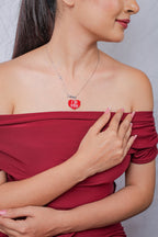 Model in a red off-shoulder top wearing the red beaded heart pendant necklace