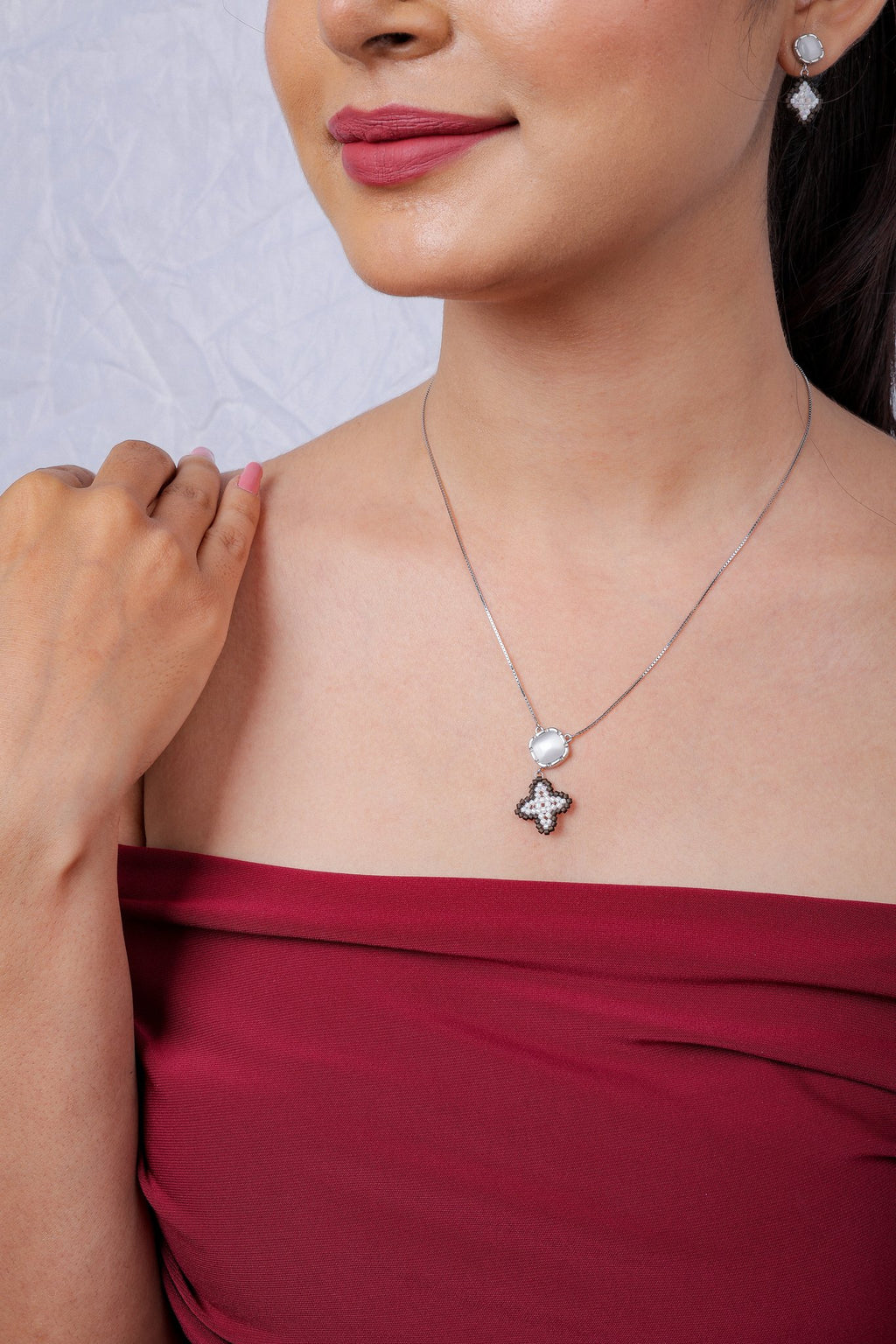 Model in red top wearing the ivory star pendant necklace with matching earring visible