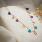 Angled view of beaded triangles, crystal teardrops and sunburst diamond charms on a rose-gold chain