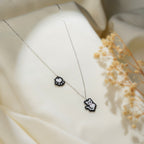 Angled view of beaded cat and paw-print charms on a fine silver chain with dried flowers