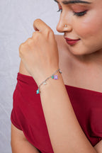 Model wearing silver bracelet with lilac and turquoise beaded charms and tiny crystal flowers