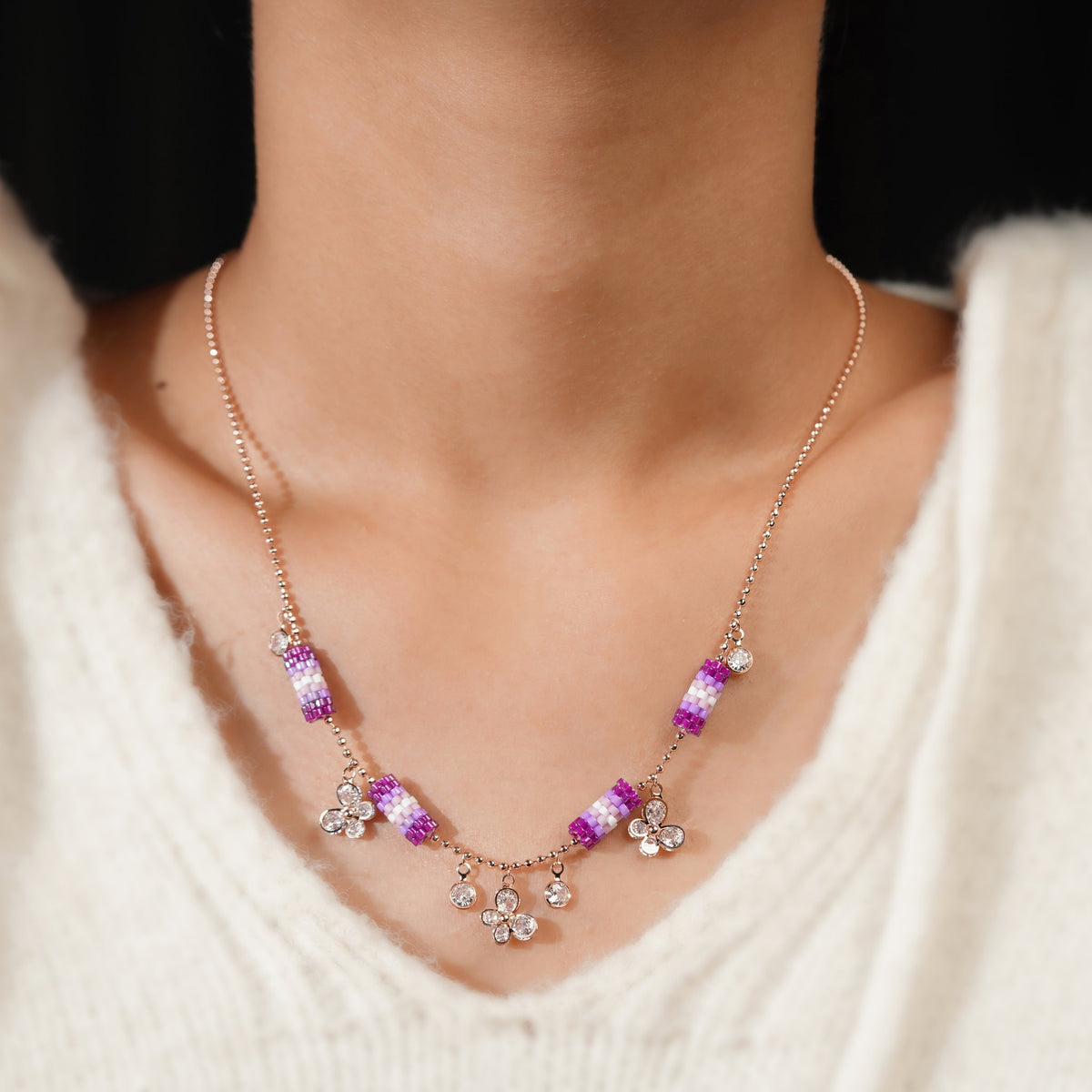 Model wearing a rose-gold-tone necklace with lilac bead tubes and crystal charms