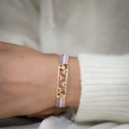 Woven lilac bead bracelet worn on the wrist with gold openwork centre plate