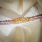 Close-up of gold openwork plate with lilac crystal butterflies on a striped woven bead band