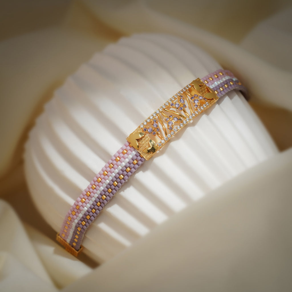 Side view of lilac and pink woven bracelet showing the gold centre plate and gold end fitting