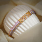 Side view of lilac and pink woven bracelet showing the gold centre plate and gold end fitting