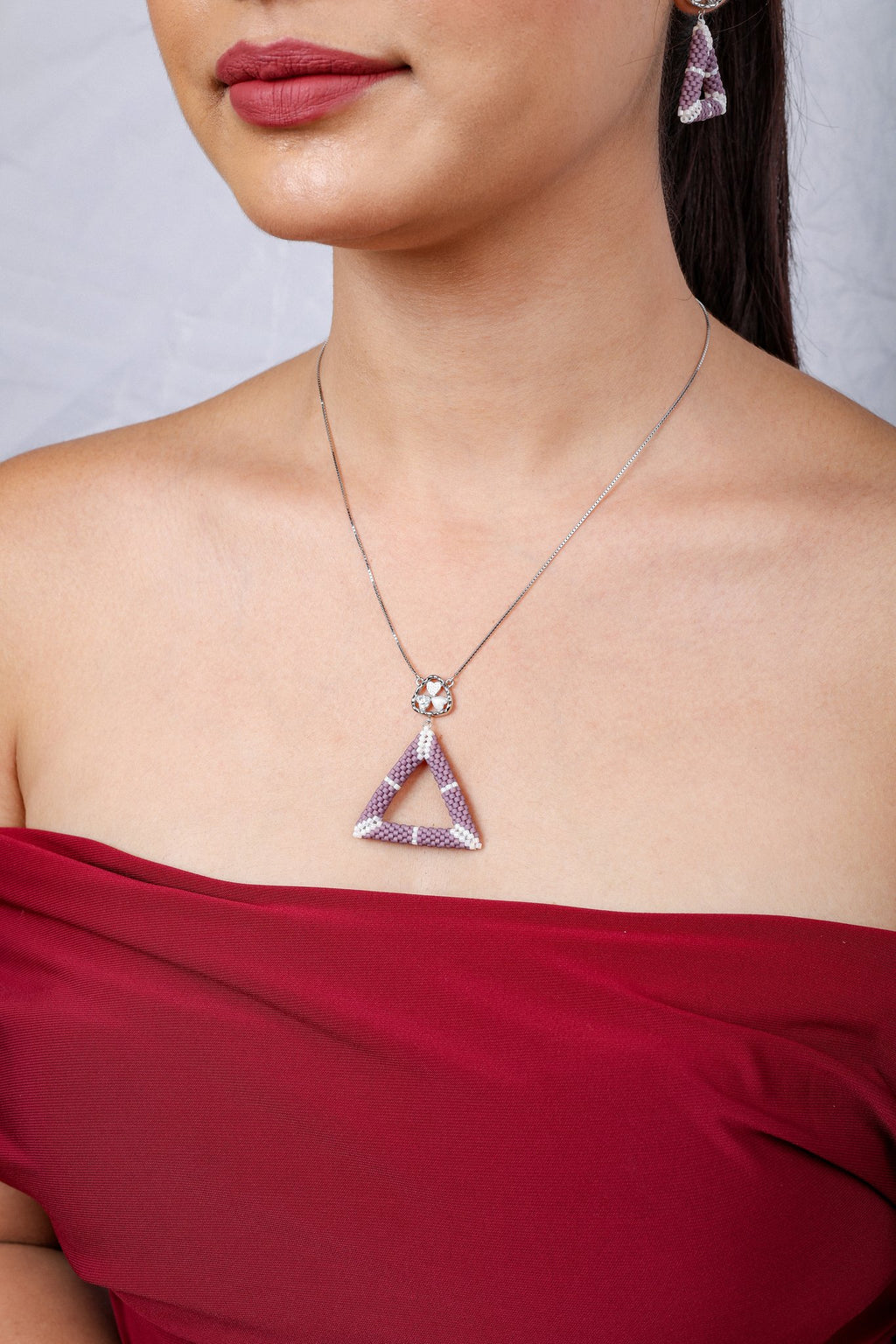 Close view of lilac beaded open-triangle pendant below a crystal heart-cluster connector