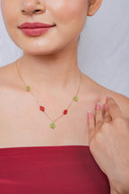 Gold chain necklace with lime-green beaded stars and red beaded diamond stations at the neckline