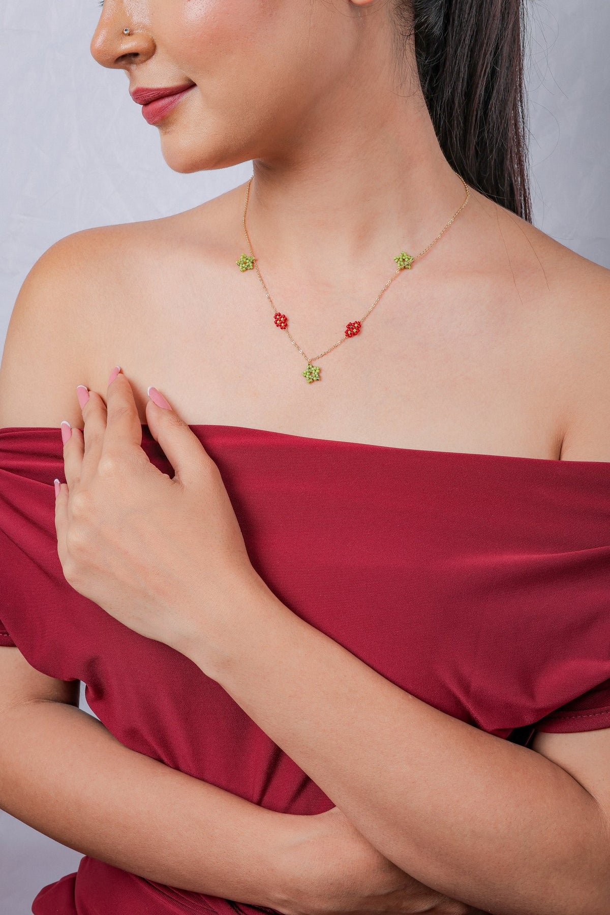 Model wearing the lime and red beaded charm necklace on a gold chain with a red top