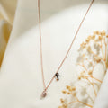 Rose-gold-tone chain with a crystal-set padlock charm and a tiny black beaded key charm