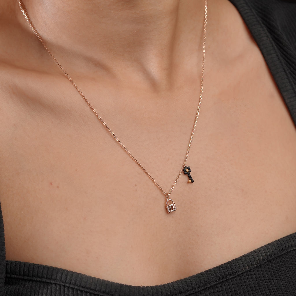 Model wearing a delicate rose-gold-tone lock and key charm necklace with a black top