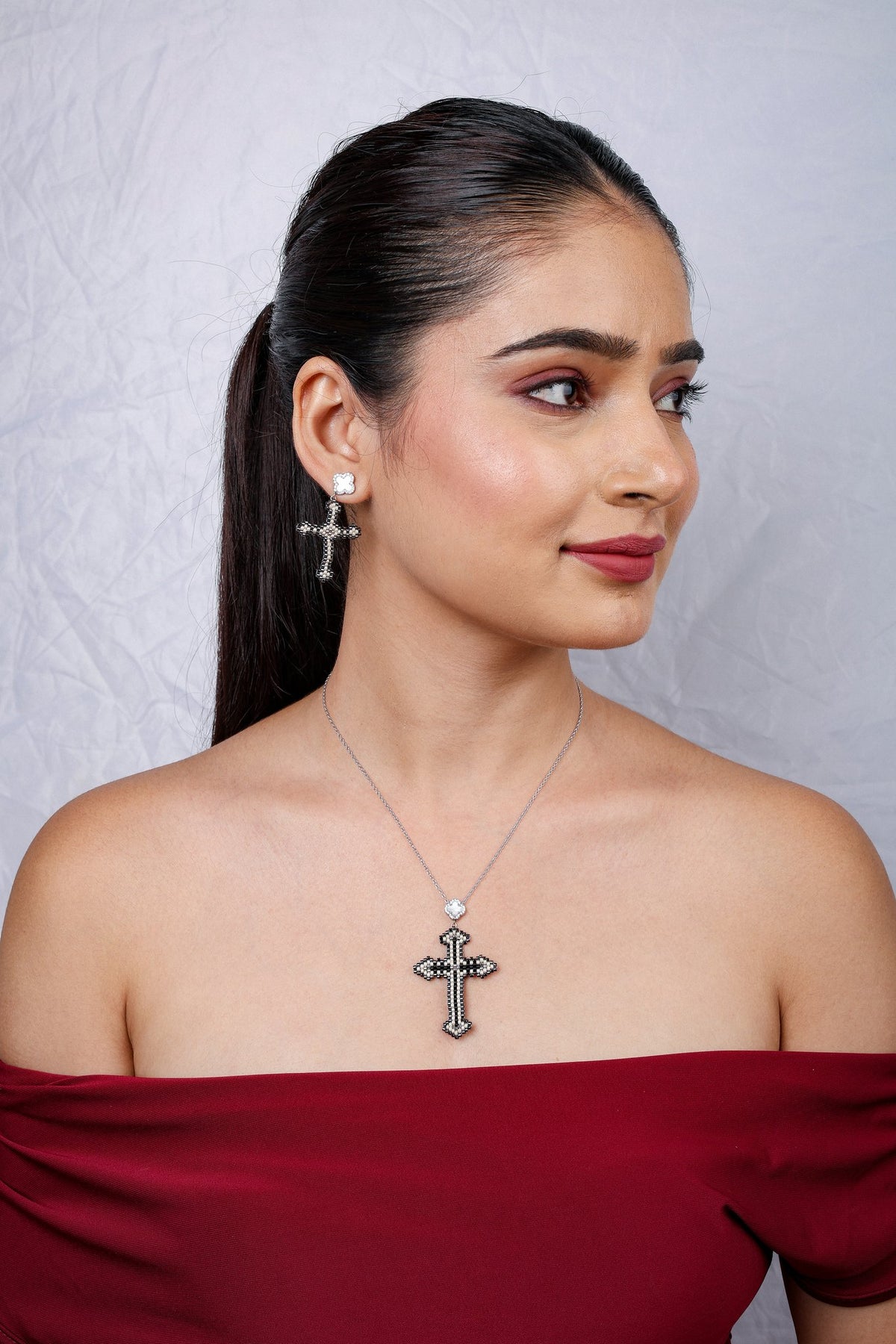 Side profile of model wearing black and ivory cross necklace and earring set