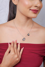 Close view of pixel-beaded white cat charm with red nose and a paw-print charm on silver chain