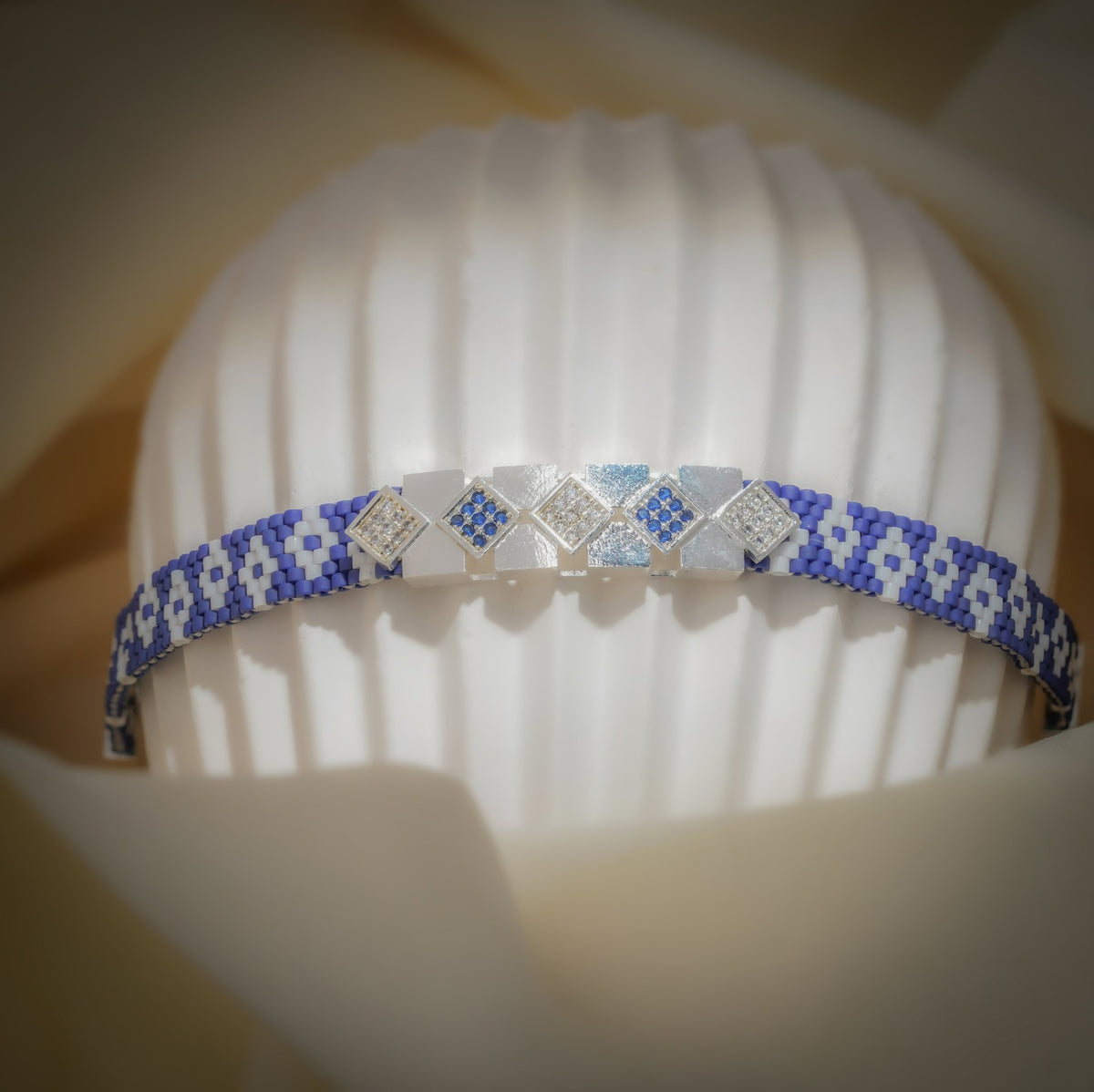 Cobalt and white woven bead bracelet with crystal-set silver-tone squares on a ribbed stand