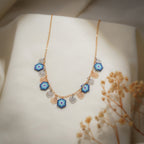 Evil-eye charm necklace draped on cream fabric beside dried gypsophila