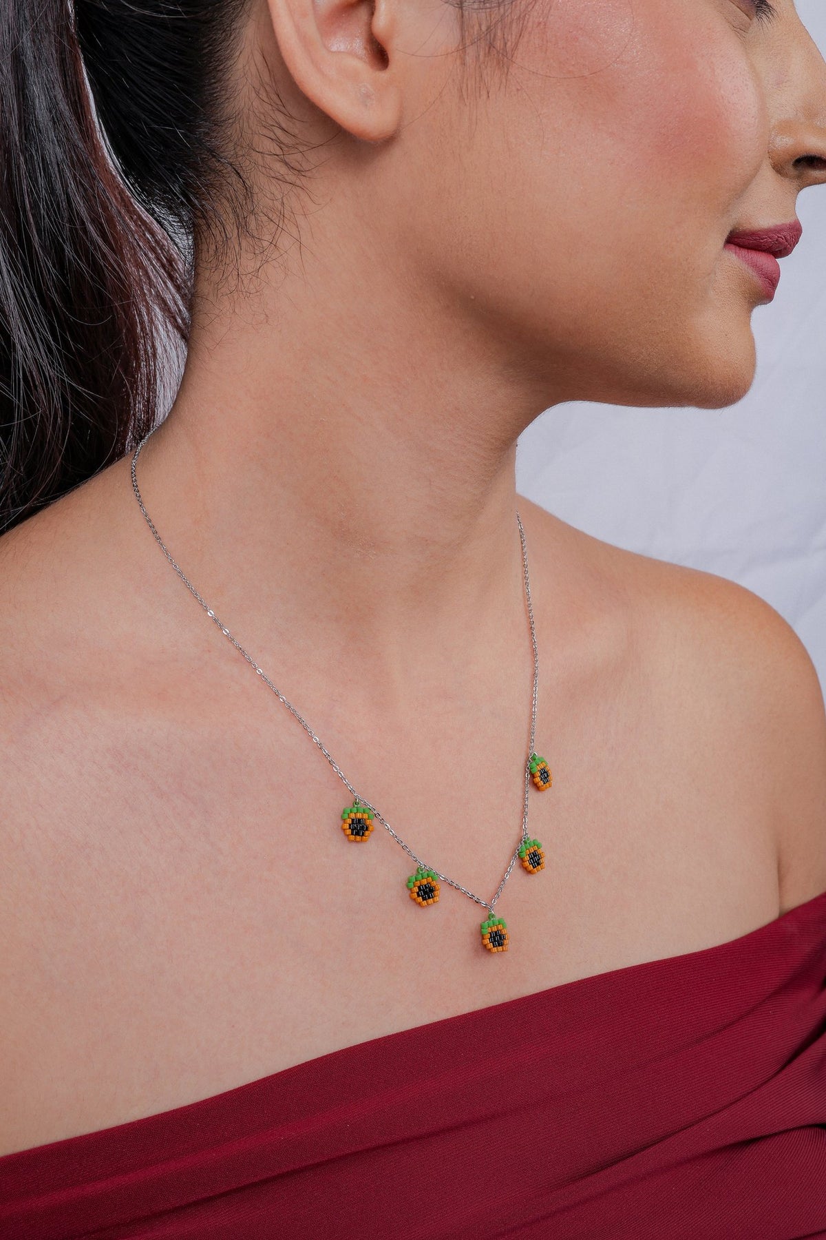 Profile view of model wearing the orange and black pixel-beaded charm necklace