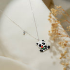 Panda pendant with red flower and crystal charm on a silver-tone chain beside dried flowers