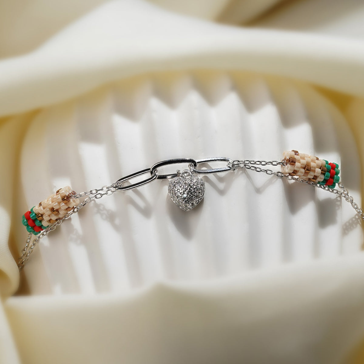 Close-up of the crystal puffed heart and cream, green and red beaded tubes on a fluted stand