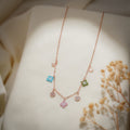 Rose-gold charm necklace with turquoise, pink and green beaded charms and crystal discs on cream fabric