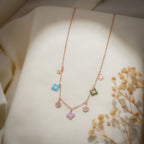 Rose-gold charm necklace with turquoise, pink and green beaded charms and crystal discs on cream fabric
