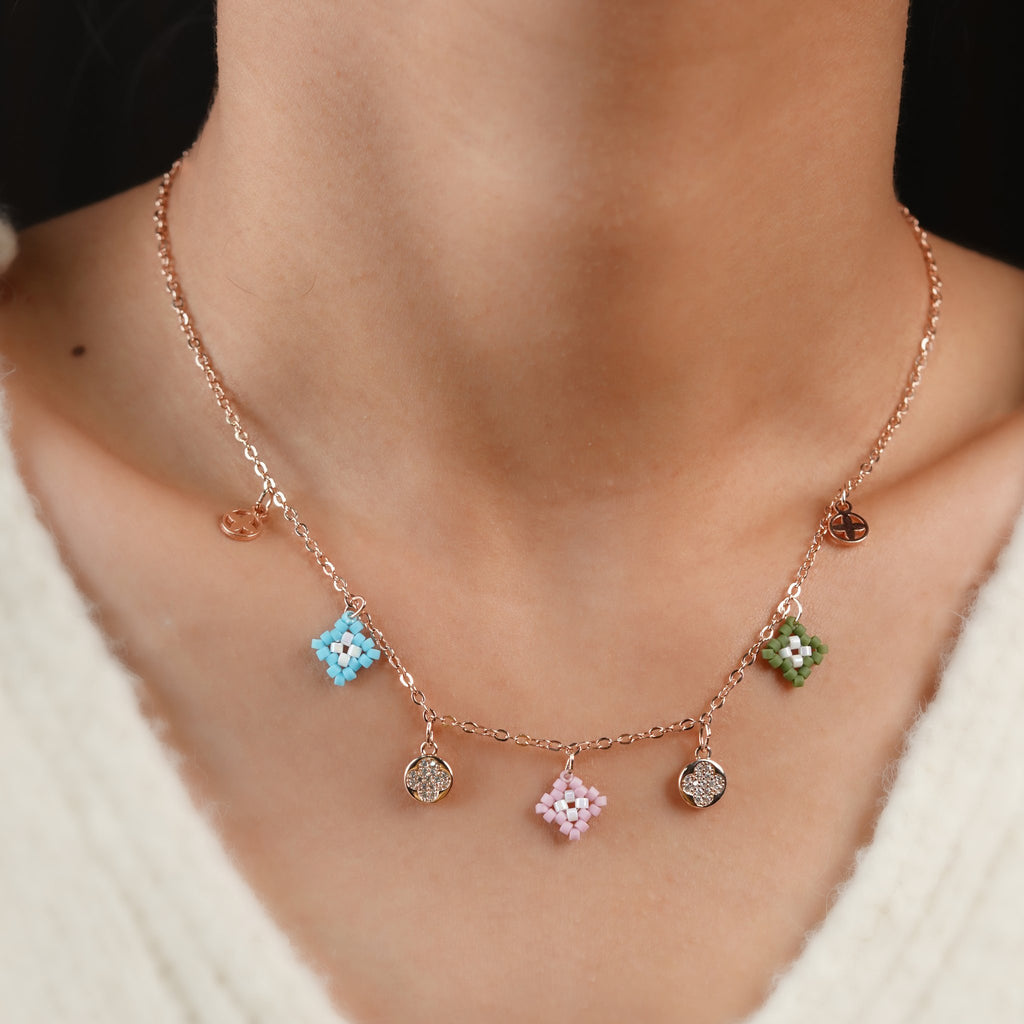 Model wearing rose-gold necklace with pastel beaded diamond charms and sparkling clover discs