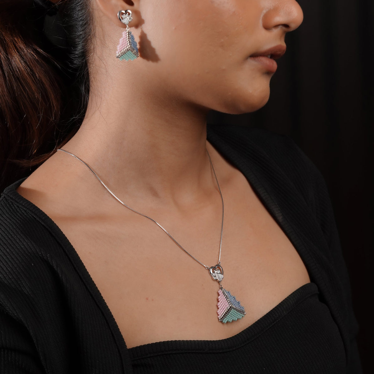 Model wearing pastel triangle drop earrings and the matching pendant necklace, side view