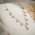 Rose-gold charm necklace with blue, pink and green beaded rhombus charms and crystal teardrops on cream silk